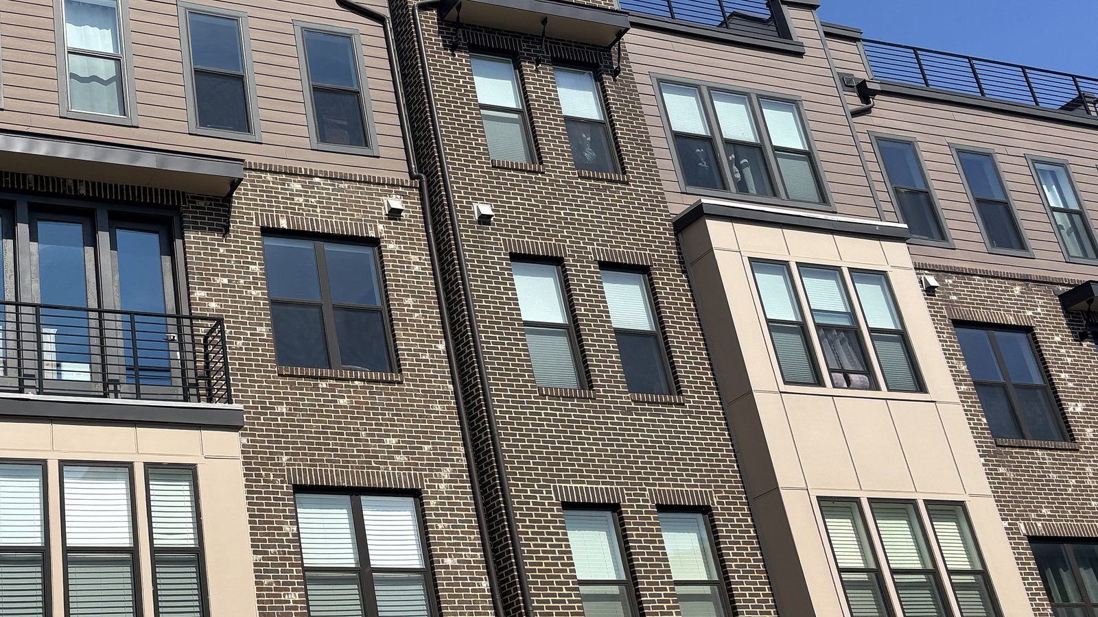 Multi-story residential building with brick masonry, panel cladding, windows and balconies