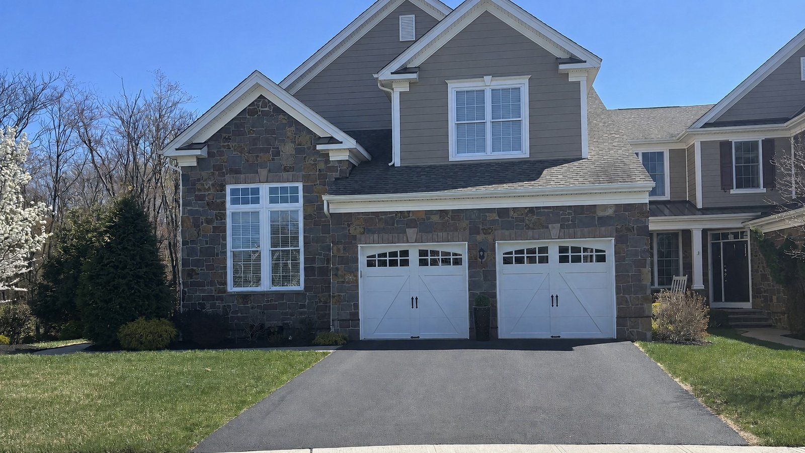 Completed detached home with stone veneer, siding, asphalt shingle roofing, and finished driveway