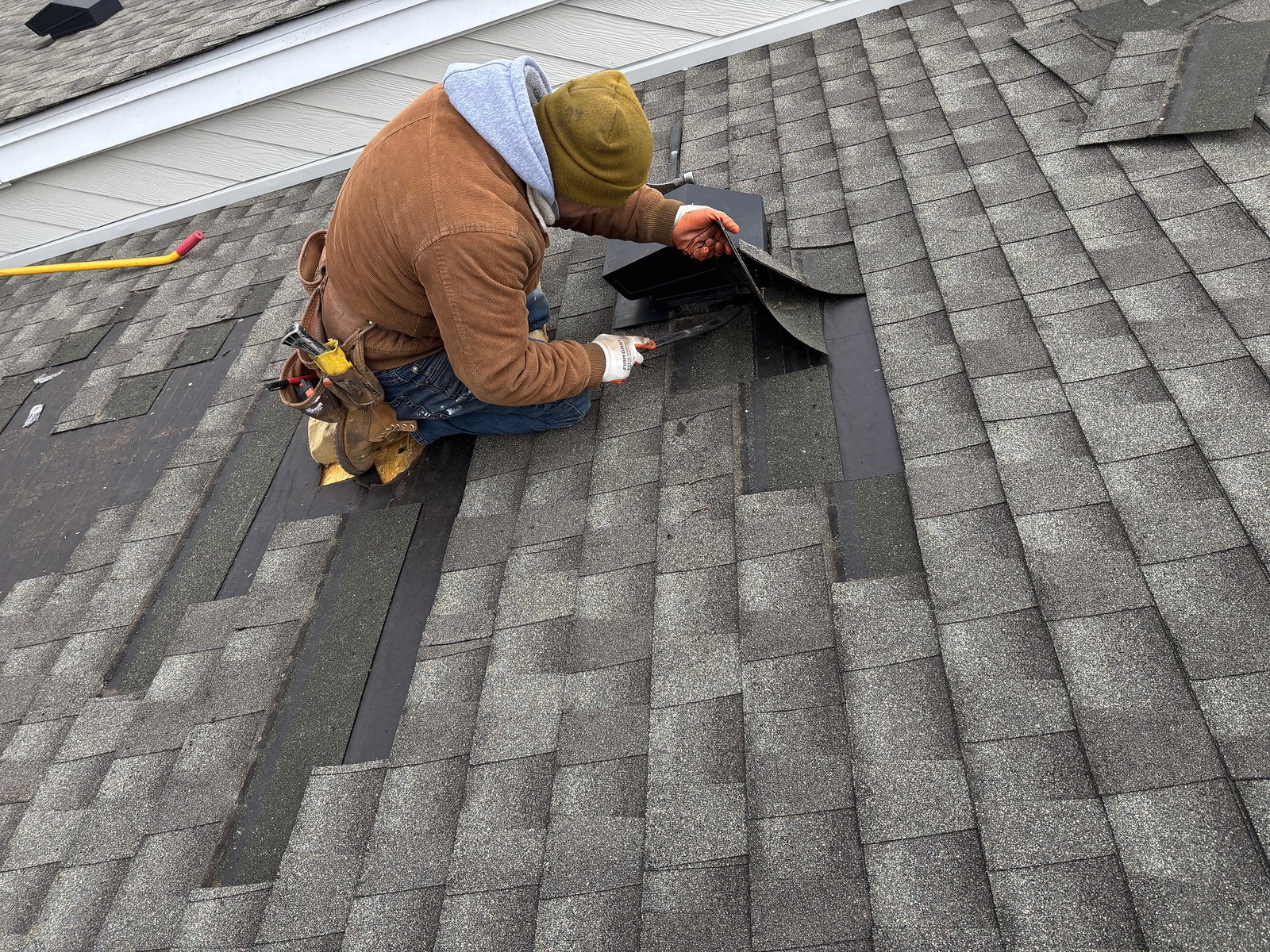 Asphalt shingle roof repair work in progress on a residential home