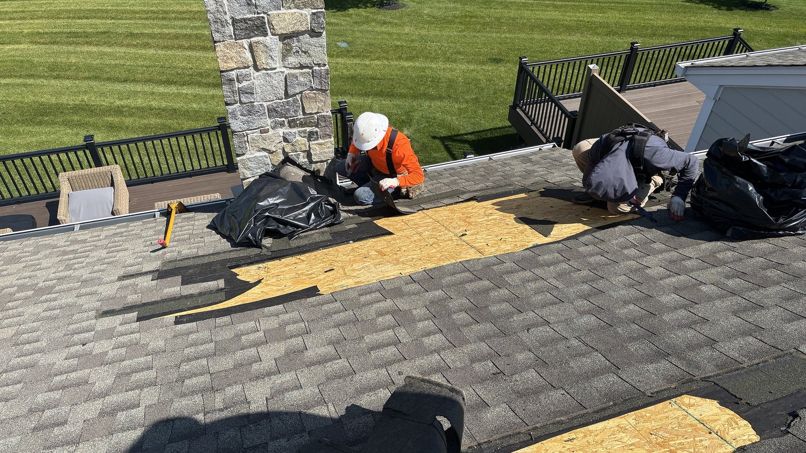 Roofing crew replacing asphalt shingles and roof decking on a residential roof